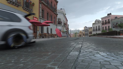 An out of focus car drifts along a cobblestoned street.