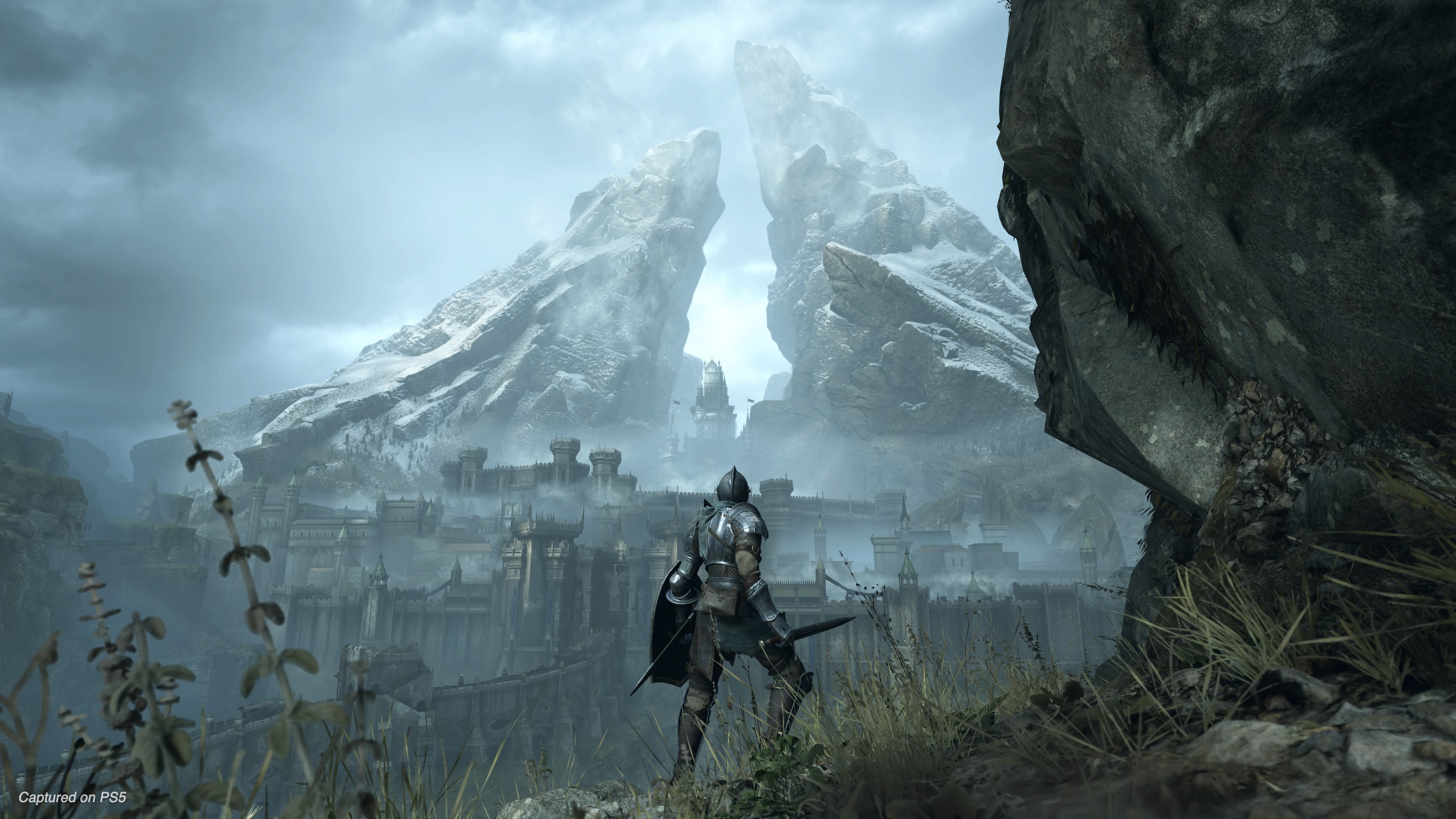 A knight looks at the landscape of a castle ahead in the Demon's Souls remake for PS5